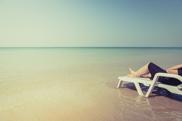 Vacation on tropical beach Woman's legs on the beach bed with clear ocean water
