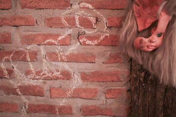 Broken Doll Face and Head hanging on brick wall decoration for Halloween party