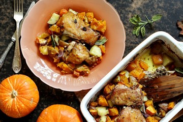 baked chicken with pumpkin and potatoes and sage. chicken pieces on a cushion of vegetables. autumn dish. orange colors. space for copy. place for text. top view