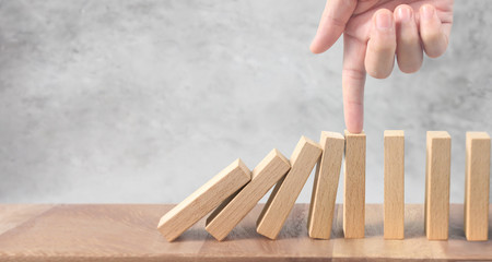 Hand stopping  Domino effect stopped by unique
