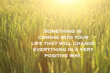 Inspirational motivational quote-Something is coming into your life that will change everything in a very positive way. With morning golden sunrise light background over the field meadow.