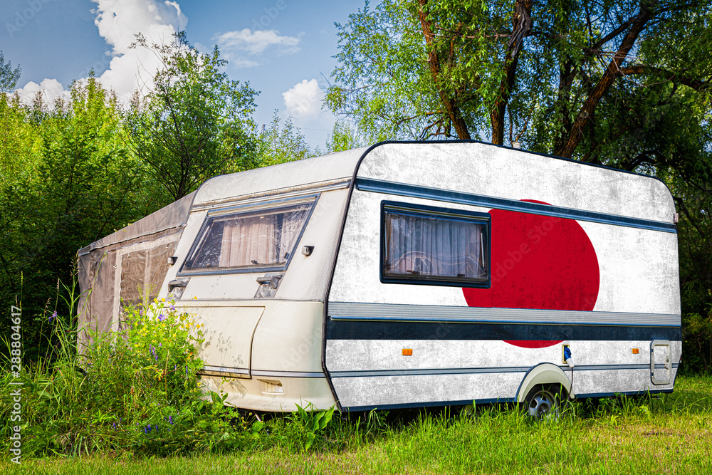 Wall mural a car trailer, a motor home, painted in the national flag of japan stands parked in a mountainous. t