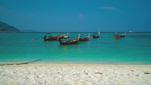 A beautiful 4K UHD Cinemagraph of a tropic seaside beach at Koh Lipe, Thailand with traditional long tail boats.