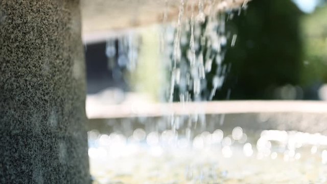 Close shot of a fountain in Slow Motion in Austria.
Water slowly dripping into fountain, pierced from sunlight.