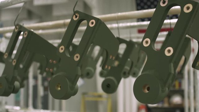 Slider shot passing a drying rack full of green powder coated parts with an American flag in the background