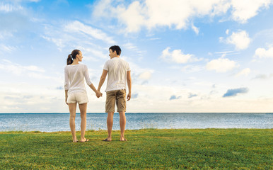 Young couple walking together holding hands at a beach park