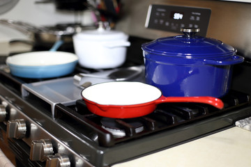 Cast iron porcelain enameled cookware on the stove top in a home kitchen.