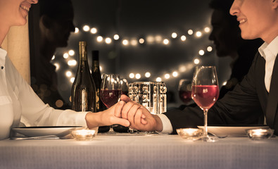Couple holding hands sitting at a restaurant table. 
