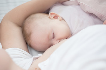 Mother holding newborn baby in an embrace and breastfeeding. Mother is breastfeeding her baby. Newborn breastfeed. Happy motherhood. Healthy eating. Happy motherhood. Caucasian child