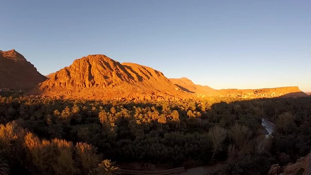 Panning left time lapse of the sun setting on the mountainside of Todra gorge with shadow cast gradually over mountains