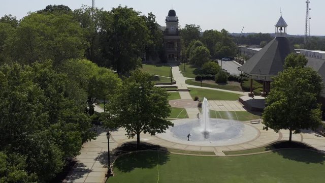 Drone's eye view of a young African American girl playing in a water fountain.