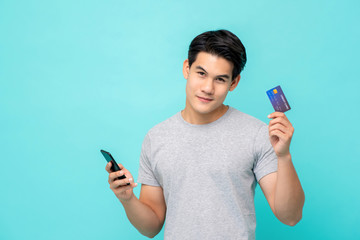 Handsome smiling young Asian man showing credit card
