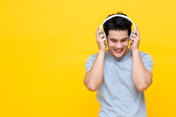 Happy young Asian man listening to music from headphones