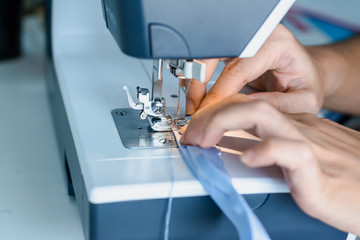   Close up dressmaker is process electric sewing machine with fabric and thread ,starting for tailor business.