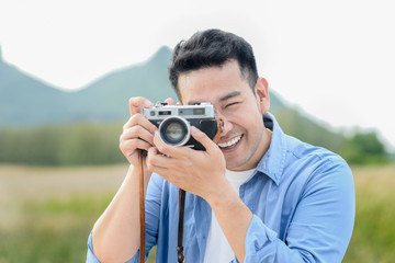 Asian photographer with vintage camera taking pictures in nature, lifestyle concept.