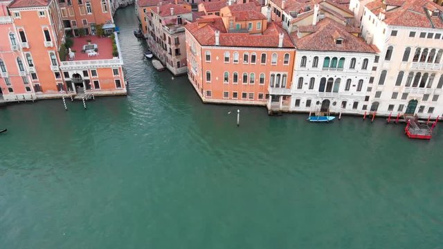In Venice Italy, the drone starts level and slowly moves up and tilts down showing the Venice Grand Canal and the tops of buildings.
