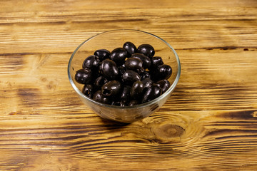 Pickled black olives in glass bowl on wooden table