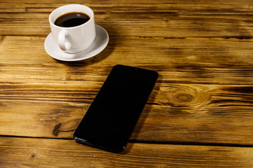 Cup of coffee and smartphone on a wooden table