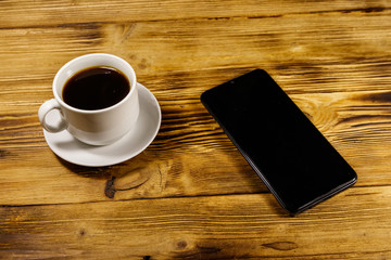 Cup of coffee and smartphone on a wooden table