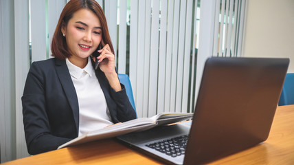 Happy smiling Business woman working in office with laptop and document while talking on phone