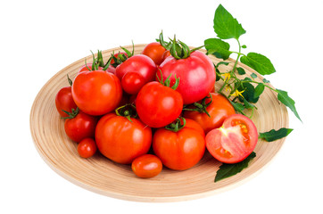Wooden dish with different ripe tomatoes on white background.