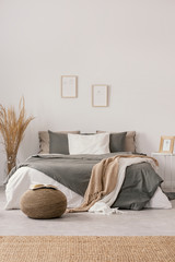 White and beige blankets on grey duvet on comfortable bed in bright bedroom interior