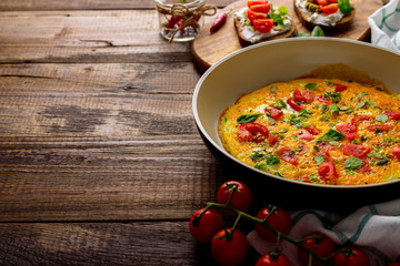 omelette with vegetables and cherry tomatoes on dark wooden background with copy space