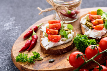 Close-up ricotta and pesto sandwiches with cherry tomatoes, chilli and herbs on a wooden Board