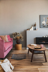 Stylish living room interior with pastel pink sofa, wooden coffee table and eco fireplace