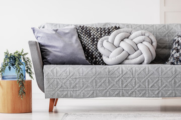 Trendy knot light grey pillow on comfortable scandinavian couch