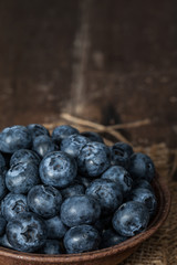 Blueberries in brown ceramic bowls placed on sacks and wooden tables with space for text.