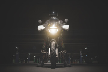 Biker sitting on his motorcycle on a night parking area. © Dmitriy