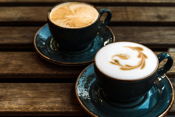 Two beautiful pink cups of cappuccino with latte art on the wooden table.