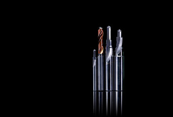 Special tools isolated on dark background. Made to order special tools. Coated step drill and reamer detail. HSS cemented carbide. Carbide cutting tool for industrial applications. Engineering tools.