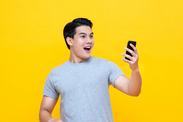 Handsome Asian man being surprised after reading message from smarrtphone