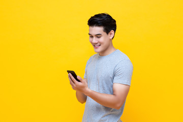 Smiling young handsome Asian man using smartphone