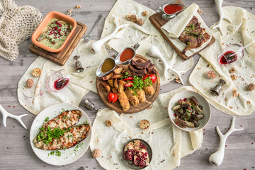 Food Table Celebration Delicious Party Meal Concept. A lot of food on the wooden table: meat, vegetables, desserts, garnishes.  Foodset from Georgian dishes. Caucasian food