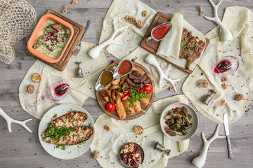 Food Table Celebration Delicious Party Meal Concept. A lot of food on the wooden table: meat, vegetables, desserts, garnishes.  Foodset from Georgian dishes. Caucasian food