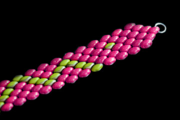 Beaded bracelet bright pink color on a dark background close up