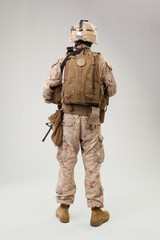 Soldier in US marines uniform with rifle on light grey background, studio shot