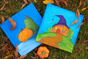 Two paintings (picture) with pumpkins (Jack-o'-lantern) and Happy Halloween theme on green grass with autumn leaves