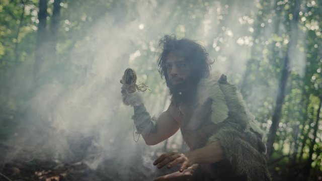 Portrait of Primeval Caveman Wearing Animal Skin and Fur Hunting with a Stone Tipped Spear in the Prehistoric Forest. Prehistoric Neanderthal Hunter Scavenging with Primitive Tools in the Jungle