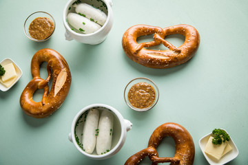 Münchener Weißwurst in Terrine mit bayrischer süßen Senf, Brezel und Butter auf Pastell grünen...