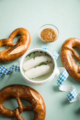 Münchener Weißwurst in Terrine und Brezel mit Oktoberfest Luftschlangen auf Pastell grünen...