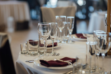 Glasses, flower fork, knife served for dinner in restaurant with cozy interior