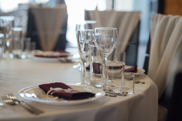 Glasses, flower fork, knife served for dinner in restaurant with cozy interior