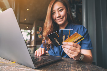 A beautiful asian woman holding credit cards while using laptop computer