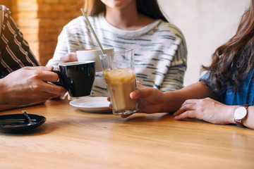 Closeup image of three people enjoyed talking and drinking coffee together in cafe