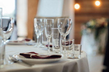 Glasses, flower fork, knife served for dinner in restaurant with cozy interior