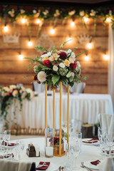 A composition of flowers and green is on a festive table at the wedding banquet hall.
